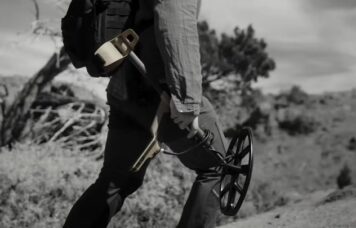 détectoriste marchant avec son détecteur replié à la main